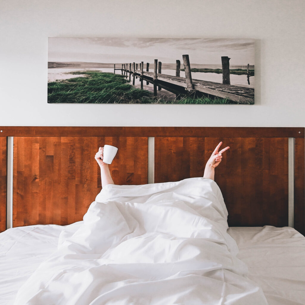 Ihminen rentoutuu sängysää peiton alla, vain kädet näkyvät